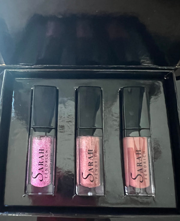 Set of three lip glosses in a black case with 'Sarah Fendrich' brand visible.